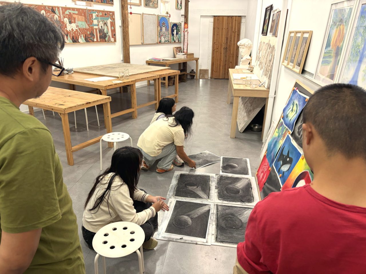 地面上的几何光影练习，孩子们围坐在一起，看同一件作品。